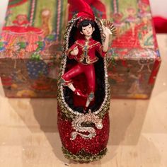 a red figurine sitting on top of a wooden table next to a box