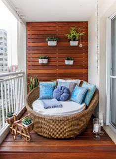 a wicker couch on a balcony with blue pillows and other decorative items around it