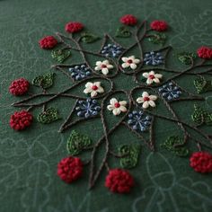 a close up of a table cloth with crocheted flowers and leaves on it