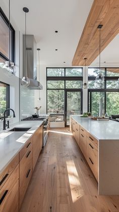 a kitchen with wooden cabinets and white counter tops, along with large windows that look out onto the woods