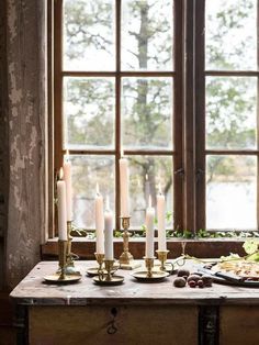 a table with candles and food on it in front of a window, next to a pane of bread