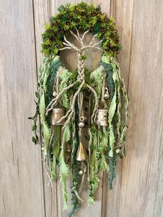 a wreath with bells hanging from the side of a wooden door covered in greenery