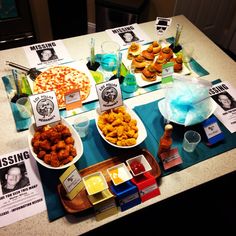 a table topped with plates and bowls filled with different types of food next to posters