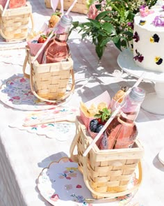 a table topped with two baskets filled with bottles of wine and fruit next to a cake