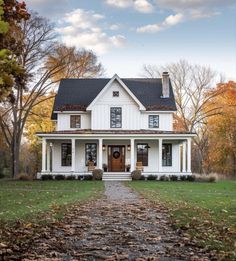 a white house in the fall with leaves on the ground