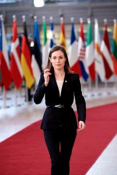 a woman walking down a red carpeted floor next to flags in an office building