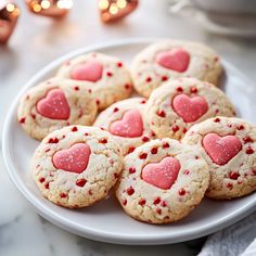 heart shaped cookies on a white plate with pink and red sprinkles in the middle