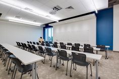 an empty classroom with desks and chairs in front of a whiteboard on the wall