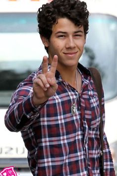 a young man making the peace sign with his hand while standing in front of a truck