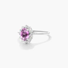 an oval shaped pink sapphire and diamond ring on a white background with the center stone surrounded by diamonds