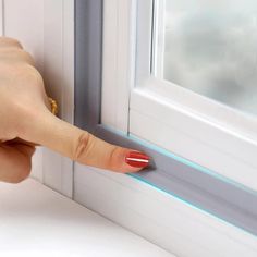 a woman's hand is touching the side of a window with her thumb on it