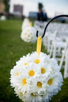 a bouquet of daisies is hanging from the back of an outdoor wedding ceremony aisle