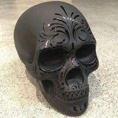 a black skull statue sitting on top of a counter next to a cell phone screen