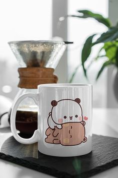 a white coffee mug with a brown bear on it sitting next to a cup of coffee