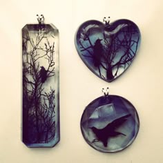 three pieces of glass with birds and branches in the shape of heart shaped pendants