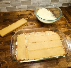 two pans filled with food sitting on top of a wooden table next to a bowl