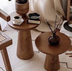 two small wooden tables with plants in them on a rug next to a chair and window