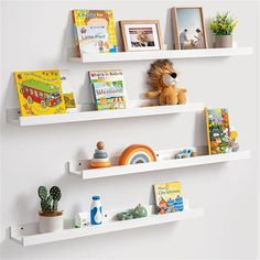 two white floating shelves with books and toys on them, one shelf has a stuffed animal