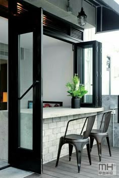 two chairs sitting on the outside of a building next to a counter with potted plants