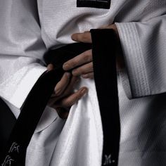 a person wearing a black belt and white kimono with their hands on the waist