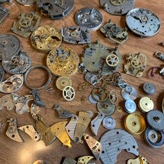 lots of old watch parts are scattered on the table top, including watches and dials