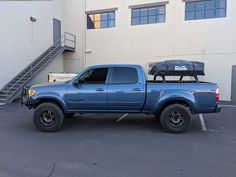 a blue pick up truck parked in a parking lot next to a building with stairs