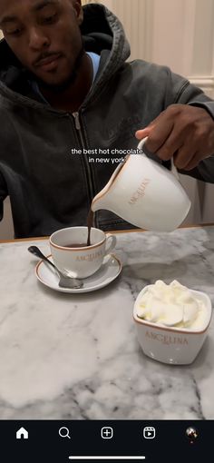 a man pours cream into a cup on top of a marble table with a white saucer