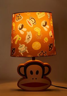 a lamp that has a monkey on it with faces all over the lampshade