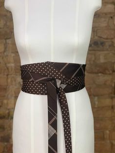 a white mannequin with a brown and black tie on it's waist