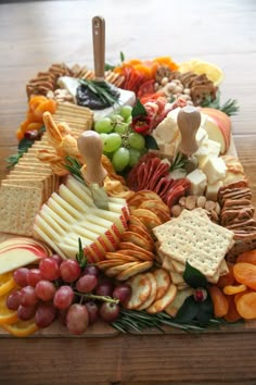 a wooden table topped with lots of different types of cheese and crackers