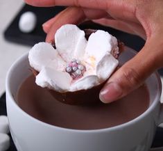 someone is dipping marshmallows into a cup of hot chocolate