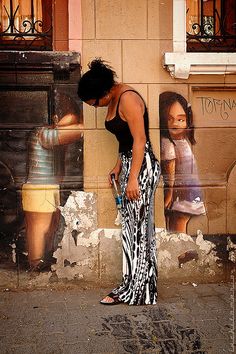 a woman standing in front of a fire hydrant on the side of a building