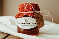 a jar filled with strawberry jam sitting on top of a white towel next to a wooden table