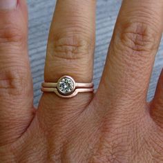 a close up of a person's hand with a diamond ring on their finger