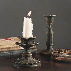 a lit candle sitting on top of a wooden table next to books and other items