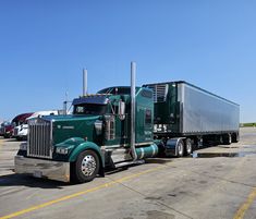 a green semi truck parked in a parking lot with other trucks behind it on a sunny day