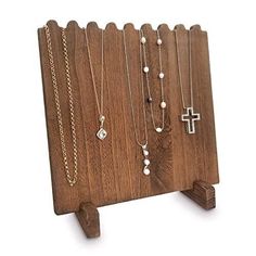 a wooden stand with several different necklaces hanging from it's sides and a cross on the other side