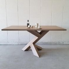 a wooden table with two cups on it next to a white brick wall in an empty room