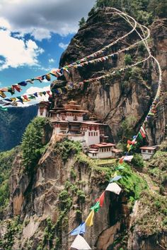 there are many flags flying in the air on top of this mountain and buildings below