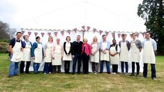 a group of people wearing aprons standing in front of a tent with flags on it