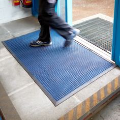 a person walking on a blue mat in front of a store door with their feet up