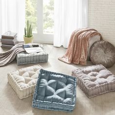 four dog beds on the floor in front of a window