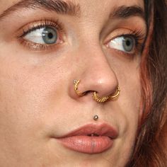 a close up of a woman with a nose ring and piercing on her nose,