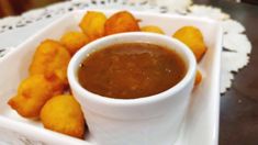 a white plate topped with tater tots next to a cup of dipping sauce