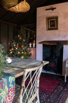 a dining room with a table and chairs next to a fire place in front of a christmas tree