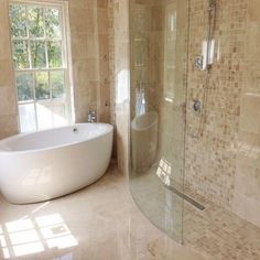 a bathroom with a large tub and walk in shower next to a window that looks out onto the outdoors