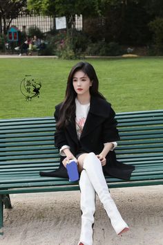 a woman sitting on top of a green bench