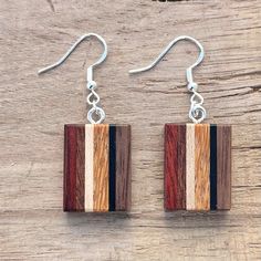 wooden earrings with silver earwires on top of a wooden table next to a piece of wood