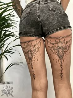 the back of a woman's thigh with tattoos on it and flowers in the middle