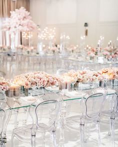 the tables are set up with clear chairs and flowers in vases on each side